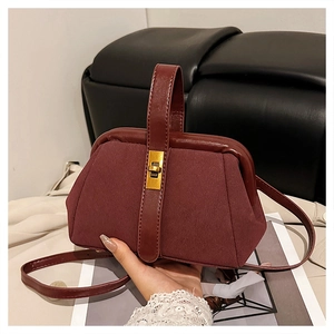 Detail of burgundy frosted suede shell bag with golden twist lock and top handle