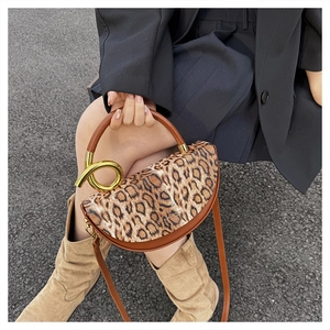 Detail of leopard print flap and golden knot metal ring buckle on brown leather handbag
