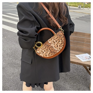 Detail of leopard print saddle bag with gold metal buckle and brown leather trim
