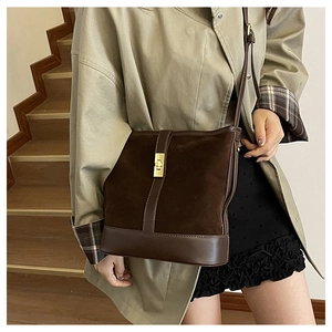 Detail view of retro brown suede shoulder bag with gold metal clasp on model