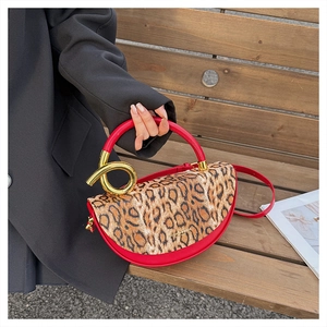 Detail of red leather crossbody bag with leopard print flap and gold spiral metal buckle