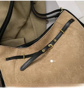 Détail du sac à bandoulière en daim camel avec lanière en cuir noir et boucle dorée