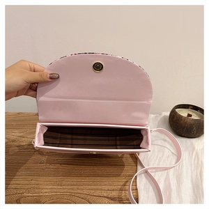 Detail view of the pink semi-circular crossbody bag showing striped interior lining