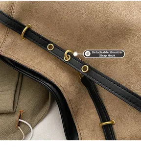 Détail de la bandoulière amovible avec crochet doré sur un sac à main en daim marron