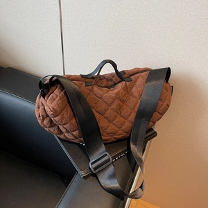 Brown quilted nylon boston bag with wide shoulder strap placed on a magazine