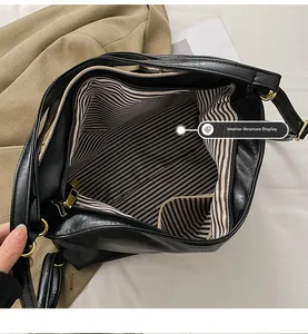 Vue interne d'un grand sac cabas noir avec doublure rayée et détails de fermeture dorée