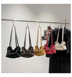 Row of minimalist suede tote bags in five colors with metal ring details and long straps
