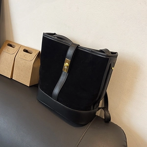 Detail of black suede and smooth leather bucket bag with a golden turn-lock closure