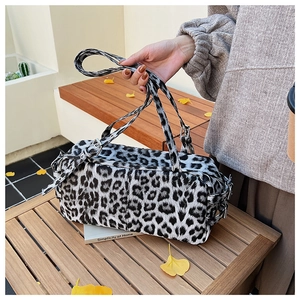 Detailed view of leopard print faux fur bowling bag on wooden bench with autumn leaves