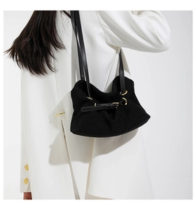 Detail of black suede dumpling bag with pleated cloud design and gold metal buckle strap