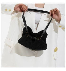 Detail of black suede tote bag with gold metal ring and buckle closure for daily styling