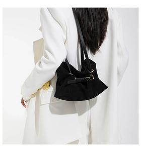 Dettaglio borsa sottobraccio in pelle scamosciata nera con fibbie dorate su blazer