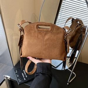 Brown suede bohemian crossbody bag featuring side tassels and eyelet shoulder strap detail