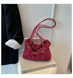 Detail of burgundy faux suede tote bag with metallic eyelets and smooth matte finish