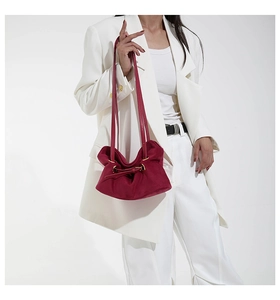Detailed view of the burgundy suede pleated shoulder bag featuring elegant gold hardware