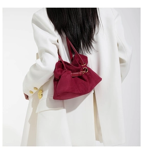 Close-up of burgundy suede tote with unique pleated design and decorative metal ring detail