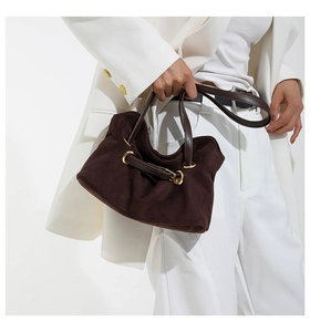 Detail of dark brown suede handbag with golden buckle and sleek leather straps