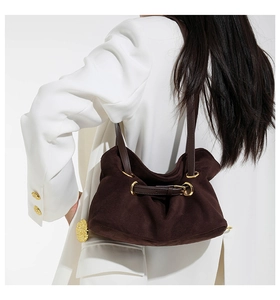 Detail of suede hobo shoulder bag with gold ring hardware and leather strap