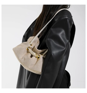 Detail of beige faux suede shoulder bag with pleated texture and gold metal eyelets