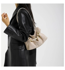 Dettaglio della borsa a secchiello in pelle scamosciata beige con occhielli dorati