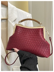 Détail du sac à main tressé bordeaux avec cadre en métal doré et poignée en bois foncé