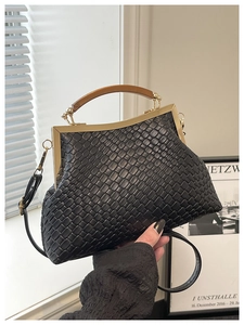 Détail d'un sac à main tressé noir avec fermoir vintage en métal et anse en bois lisse