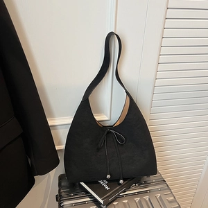 Large black suede hobo tote bag with bow tie detail on a silver suitcase