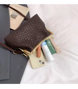 Gros plan d'un sac tressé marron foncé montrant l'intérieur spacieux et le fermoir doré