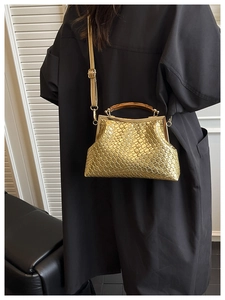 Détail du sac à main tissé doré avec poignée ambre et texture métallique en grille