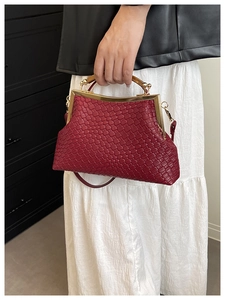 Gros plan sur la texture tressée bordeaux du sac vintage avec fermoir doré chic