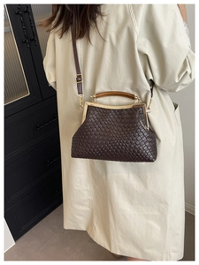 Détail d'un sac tressé marron foncé avec fermoir vintage et poignée en bois poli