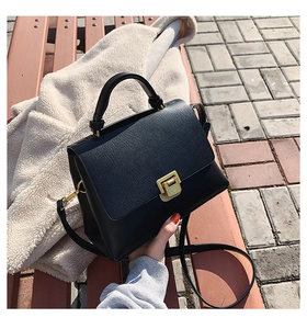 Détail du sac à bandoulière vintage noir avec boucle dorée posé sur un banc de parc