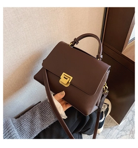 Detail of dark brown vintage faux leather crossbody bag with golden buckle and top handle
