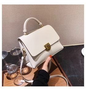 Detail of a beige trapezoid handbag with gold metal lock and fine synthetic leather texture