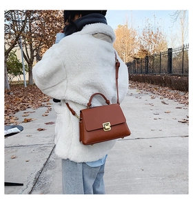 Caramel retro square crossbody bag with gold hardware shown on person in outdoor setting