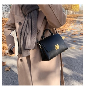 Détail d'un sac bandoulière noir structuré doté d'un fermoir doré carré en métal chic