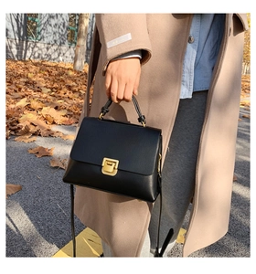 Détail d'un sac à main vintage en cuir noir avec un fermoir carré en métal doré