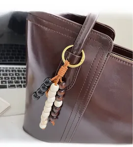 Close-up of retro wooden bead pendant on a dark brown leather tote bag with gold ring