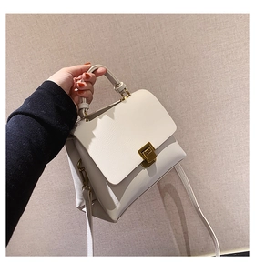 Detailed close-up of white leather handbag with gold rotary lock and top handle