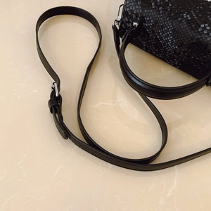 Detail of black faux snakeskin handbag with silver hardware and adjustable strap