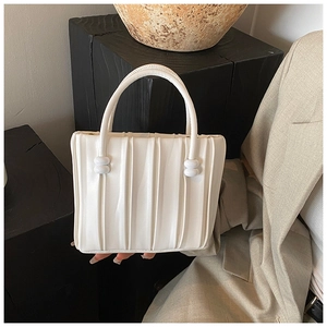 Detailed close-up of the vertical pleated texture on an off-white leather handbag