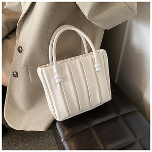 Close-up of pleated beige faux leather handbag with elegant vertical texture and top handle