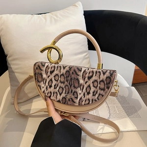 Saddle handbag with leopard print flap and unique gold metal handle on a magazine