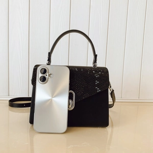 Mini black snakeskin pattern handbag shown with a smartphone for precise size comparison