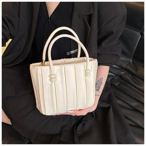 Detailed view of cream pleated handbag with beaded handles and vertical soft texture