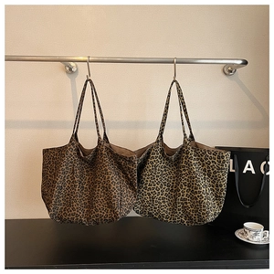 Detail view of two vintage leopard print canvas tote bags hanging on a rack display