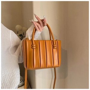 Detailed view of ginger yellow pleated handbag with PU leather texture and shoulder strap