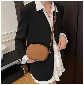 Detail of vintage brown suede crossbody bag featuring gold zipper and slim strap on model
