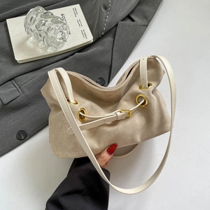 Minimalist beige suede shoulder bag with gold metal eyelets and white leather strap