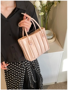 Pink pleated leather tote bag with unique spherical handle detail held by model